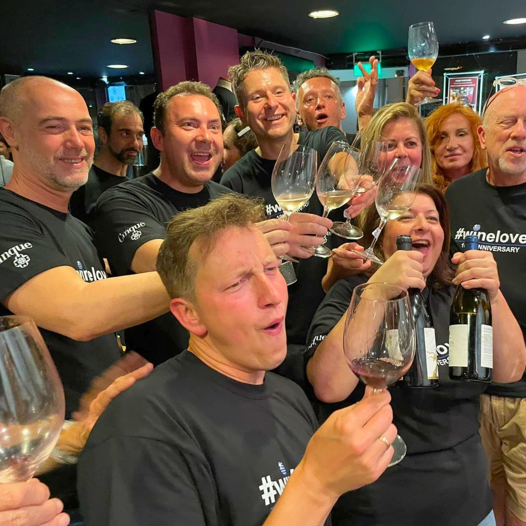 Group of guests enjoying a Greek wine experience and raising glasses at a Cinque event.