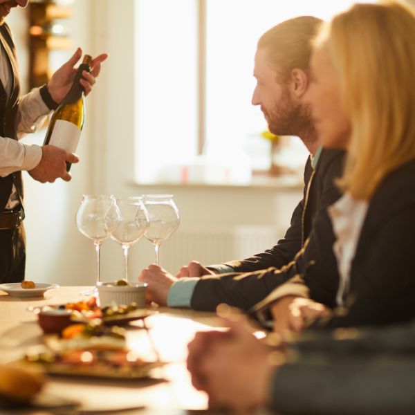 Wine presenter introducing a bottle of wine to guests during a professional tasting and hospitality experience.