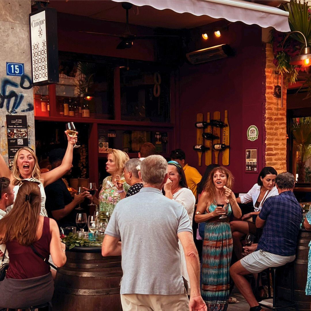 Busy wine bar terrace with guests enjoying Greek wine and hospitality in Athens.